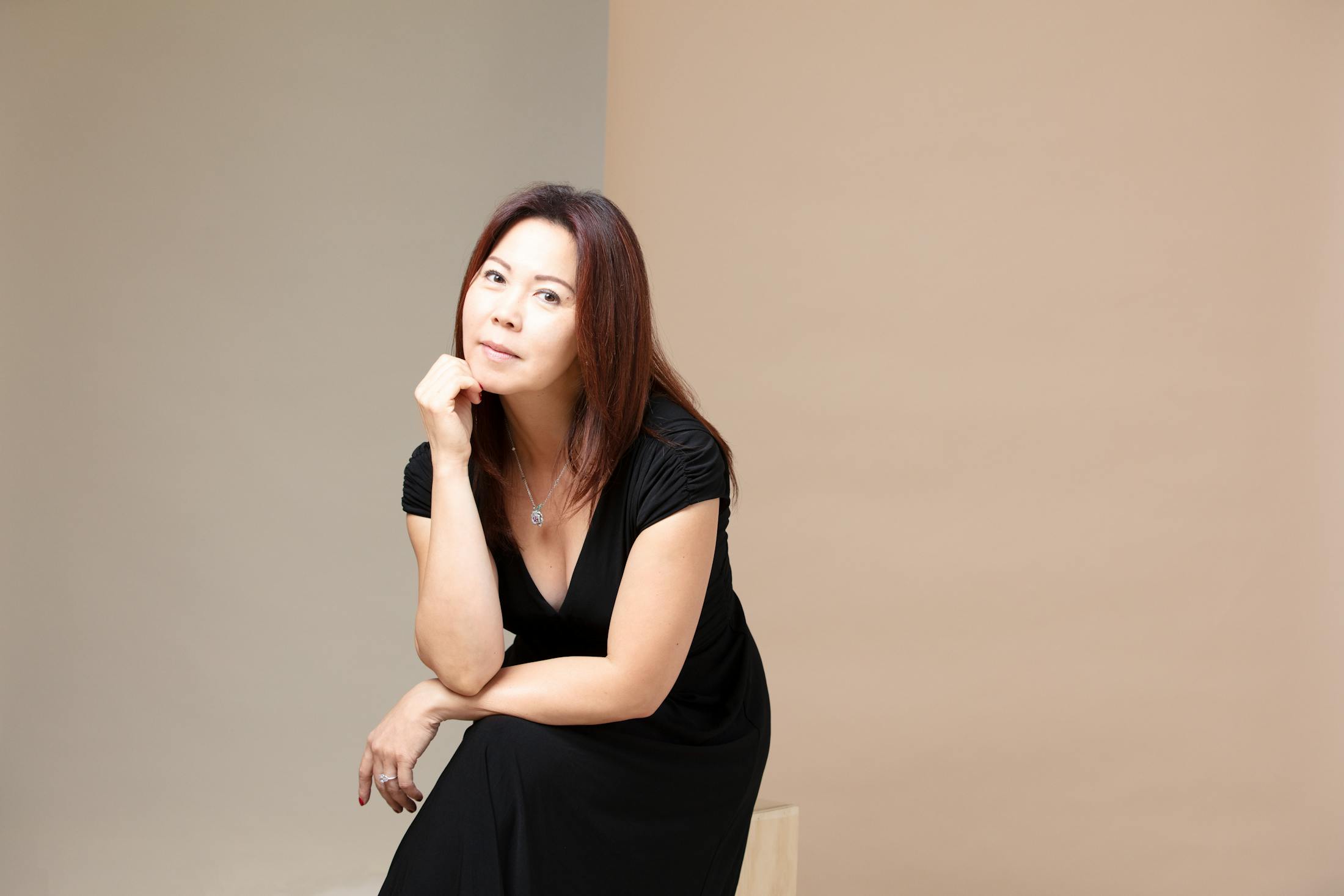 Woman in a black dress with her hand on her chin