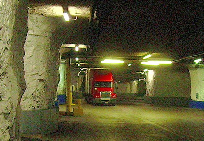 A colorful photograph of a red truck driving through a dimly lit cave.
