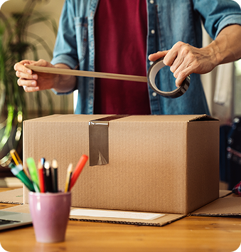 Person taping a shipping box closed.
